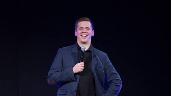 Rūdolfs Kugrēns stāv ar mikrafonu rokās 