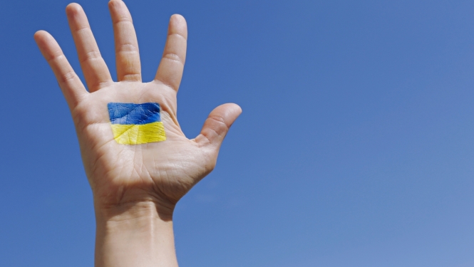 foto ar cilvēka pacelt roku uz kuras uzzīmēts ukrainas karogs 