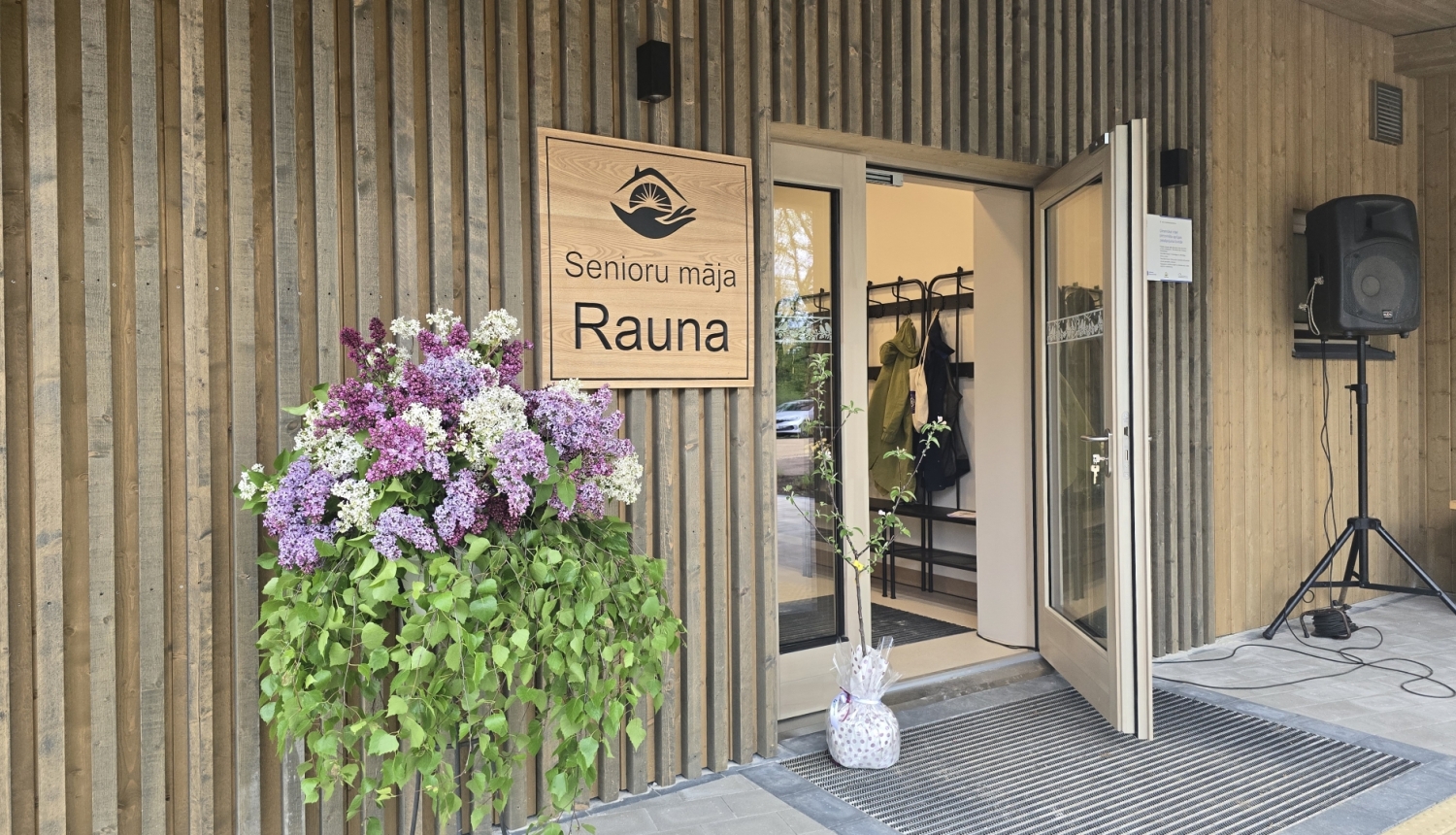 foto ar raunas senioru mājas ieejas durvīm 