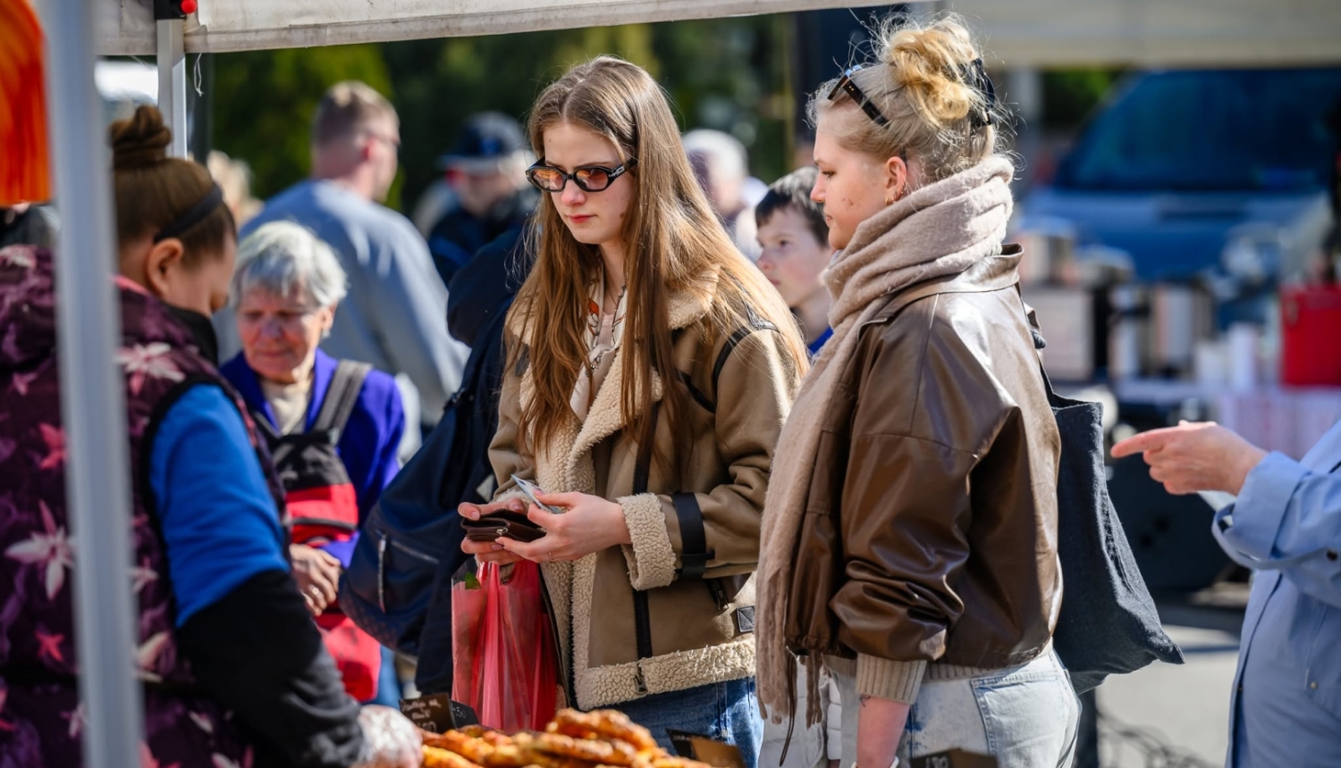 foto ar cilvekiem kas stāv pie tirgotāja gadatirgū
