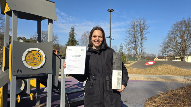 foto ar juridiskās nodaļas pārstāvi aktīvās atpūtas parkā, rokās balva 