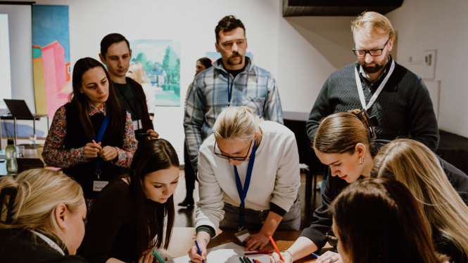 attēlā cilvēki pie galda apspriežas, ģenerē idejas