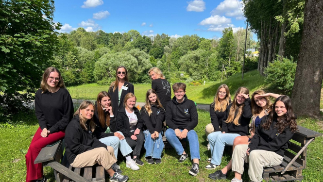 Jaunieši vienā rindā sēž  pie dabas