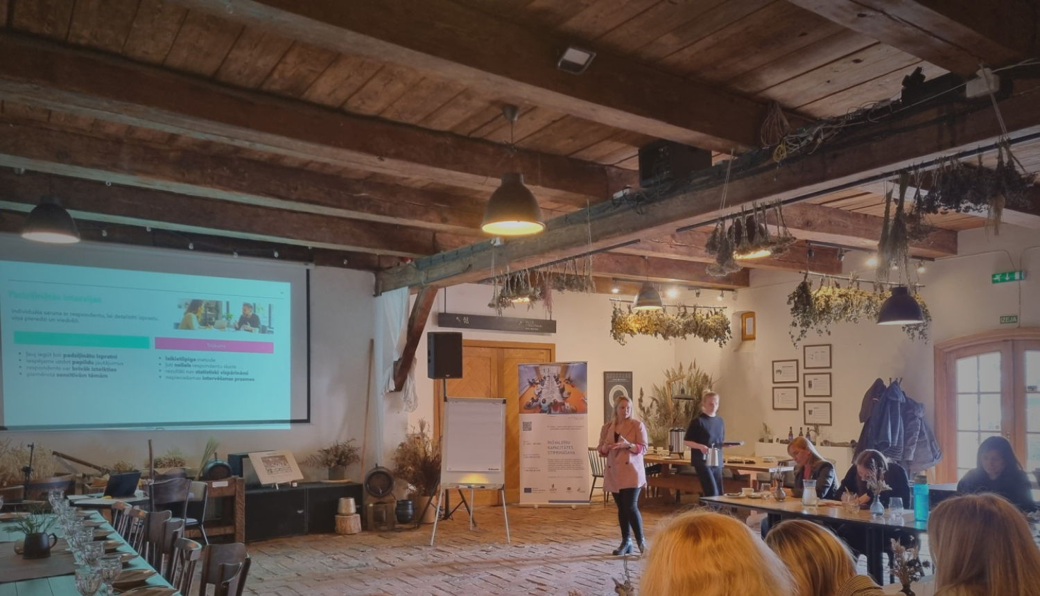 foto ar cilvēku auditorijas priekšā, kas prezentē prezentāciju 