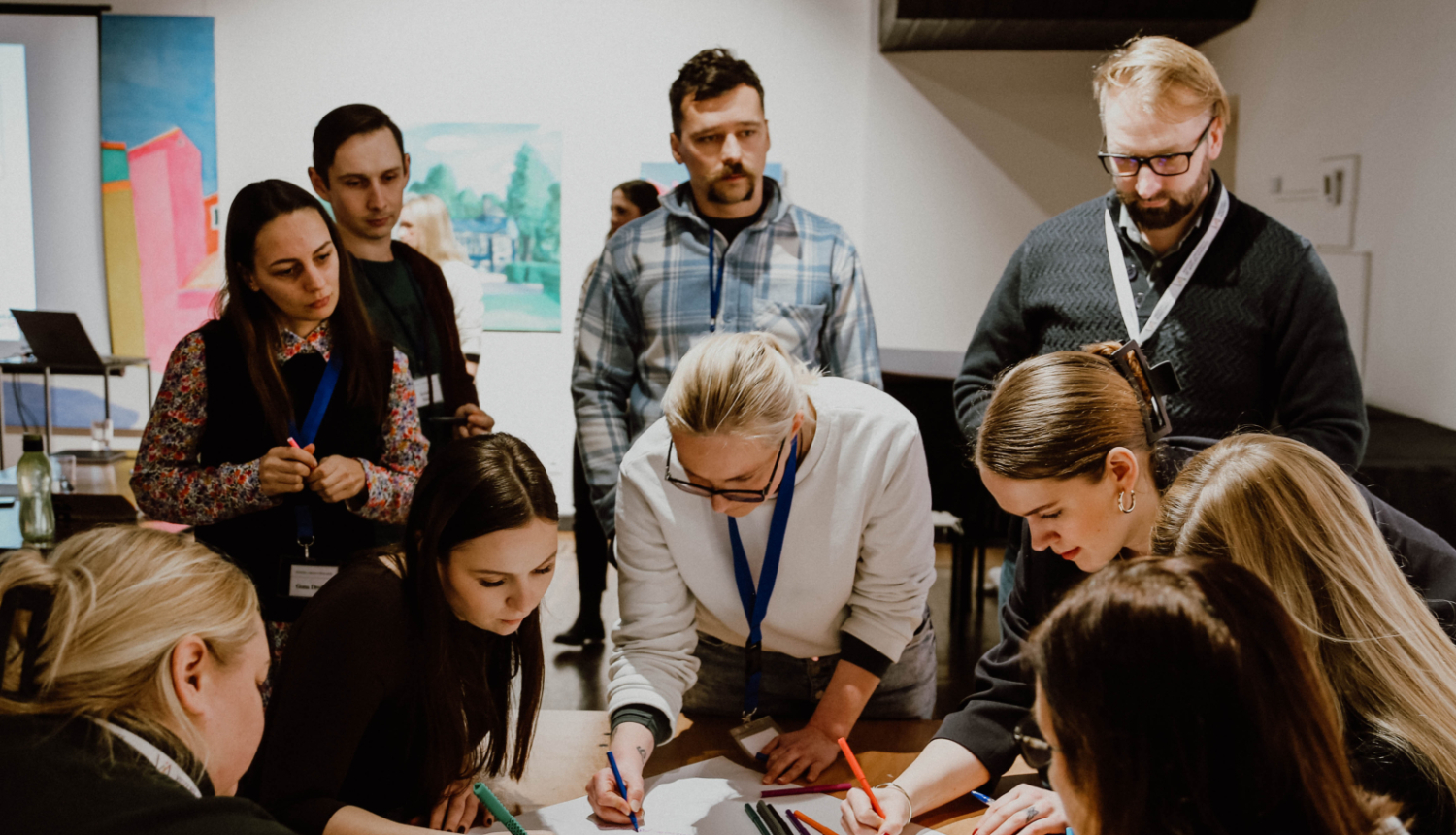 attēlā cilvēki pie galda apspriežas, ģenerē idejas