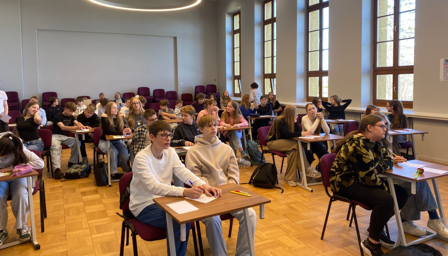 foto ar kolēnime kas sēž pie galda zālē